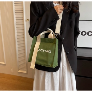 Detailansicht der grünen Canvas-Eimertasche mit J CHAO-Druck und verstellbarem cremefarbenem Gurt