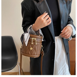 Detailed view of brown quilted bucket bag with gold flower hardware and silk scarf