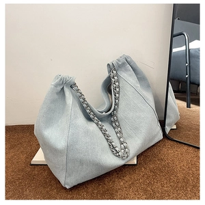 Détail du grand sac cabas en jean bleu clair avec bandoulière en chaîne argentée