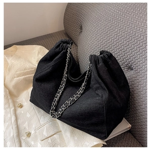 Détail du sac cabas en denim noir avec cordon de serrage et bandoulière en chaîne