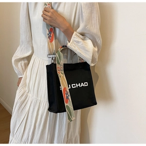 Detail der schwarzen Canvas-Beuteltasche mit buntem floralem Jacquard-Schultergurt