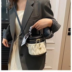 Close-up of quilted cylinder bucket bag with camellia hardware and silk scarf detail
