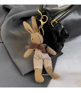 Detail of a brown knitted bunny charm with plaid overalls on a black cylinder bag