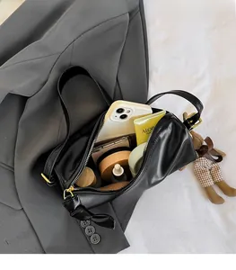 Detail view of large interior capacity of black cylindrical bag with teddy bear charm