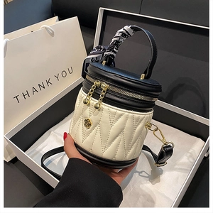 Close-up of quilted cream bucket bag with black leather accents and silk scarf handle