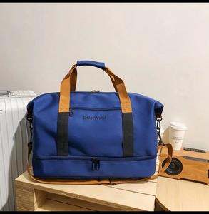 Detail der blauen Oxford-Reisetasche mit separatem Schuhfach unten auf Holzoberfläche
