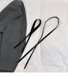 Detail showing dual detachable shoulder straps on a minimalist textured cylinder bag