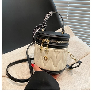 Detailed quilted bucket bag with silk scarf handle and golden flower charm accessory