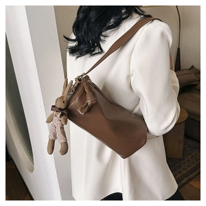 Brown leather cylinder shoulder bag with a cute knit bunny pendant and bow detail