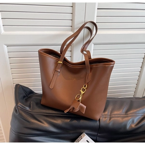 Detail of a brown leather tote bag with gold hardware and a cute elephant charm
