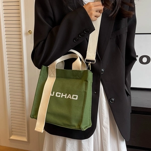Waldgrüne Canvas Eimertasche mit breitem Gurt und weißem Schriftzug für modernen Alltag