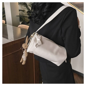 Detail of white cylinder shoulder bag with a bow knot and cute bunny charm on black blazer