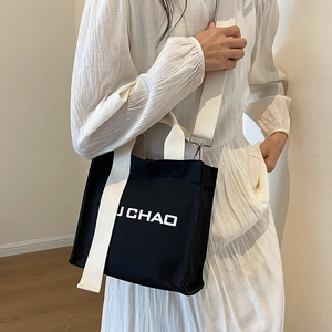 Minimalistische schwarze Segeltuch-Beuteltasche mit JCHAO-Druck und cremefarbenem Gurt