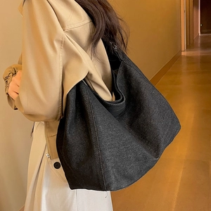Grand sac cabas en denim gris foncé avec chaîne porté par un mannequin dans un décor chic