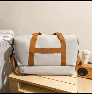 Detail der grauen Oxford-Reisetasche mit unterem Schuhfach und braunen Trageriemen