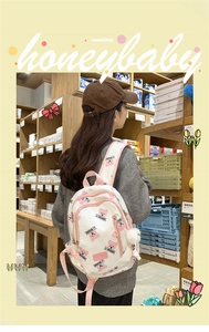 Detail view of large white canvas backpack with pink bear print and adjustable straps
