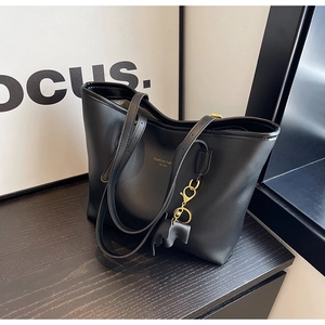 Detail of black leather tote bag with gold lettering and small elephant charm accessory