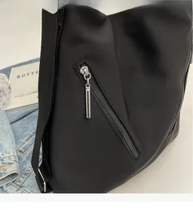Close-up of smooth silver metal zipper on a black nylon tote bag with denim background