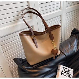 Detail of a color-block tote bag with leather elephant charm and adjustable straps