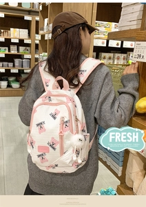 Quilted white backpack with pink cartoon bear prints and plush pendant on model