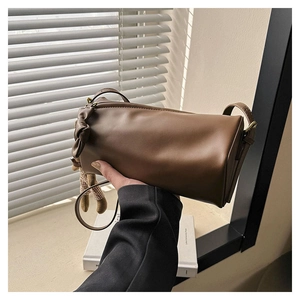 Detail of brown cylindrical crossbody bag with side bow decoration and matte leather finish
