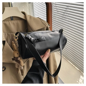 Detail of black cylinder leather bag featuring a bow and a rabbit doll charm hanging