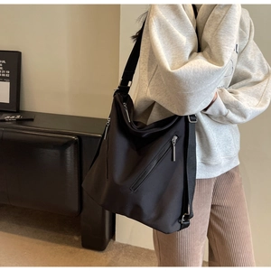 Detail of black large capacity tote bag with front diagonal zippers and wide shoulder strap