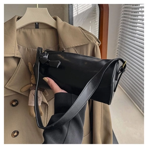 Detail view of black cylinder shoulder bag with side knot decor and smooth leather finish
