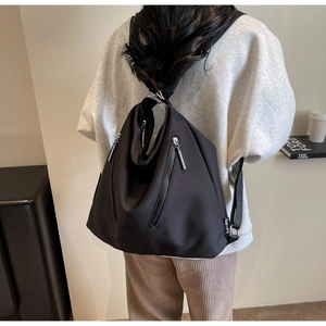 Model wearing black waterproof nylon backpack with dual vertical metal zippers detail