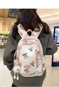 Quilted white backpack with pink bear prints and a soft plush ball charm accessory