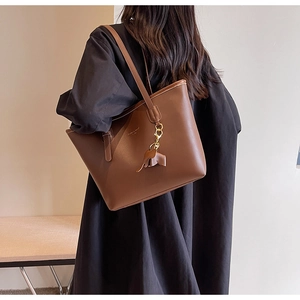 Detailed back view of a brown leather tote bag with elephant charm on model
