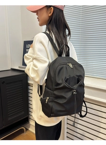 Detail of a large black nylon backpack featuring drawstring pleats and side anti-theft pockets