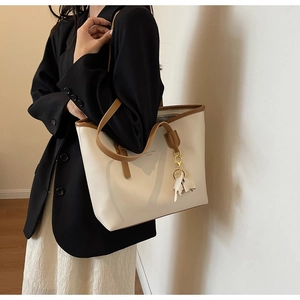 Detail of white PU leather tote bag with camel straps and a horse charm accessory