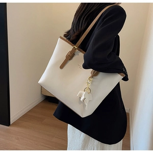 White large capacity tote bag with brown trim and elephant charm shown on a model