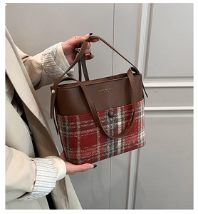 Detail of wool plaid fabric and leather handle on a vintage texture tote bag