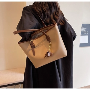 Side view of a large khaki and brown tote bag with fashion lettering and bow charm