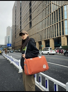 Sac de voyage en nylon orange avec bandoulière réglable grise et écusson brodé