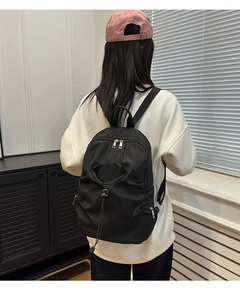 Rear view of a large black fashion backpack on a model in a modern interior