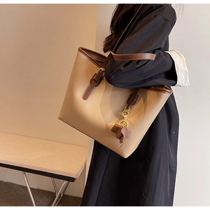 Detail of large tote bag with beige-brown color block and cute elephant charm