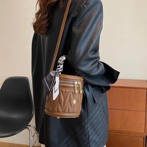 Brown quilted bucket bag with gold floral charm and printed silk scarf detail