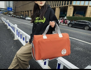 Détail du sac de voyage Oxford orange avec poignées grises et écusson 1979 brodé