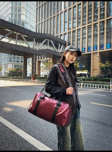 Detail of burgundy oxford travel bag featuring waterproof fabric and top handle straps