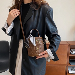 Brown quilted bucket bag with V-shaped stitching and floral charm decoration