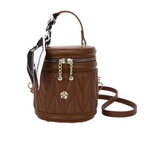 Brown mini bucket bag with diamond quilting and silk scarf handle on white background