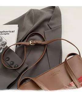 Detailed view of brown leather bag with red plaid fabric and adjustable strap buckles