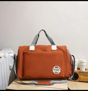 Détail du sac de voyage en tissu oxford orange avec logo AMA 1979 et sangles grises