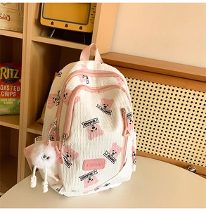 Detailed close-up of quilted white backpack with pink cartoon bear and plush charm