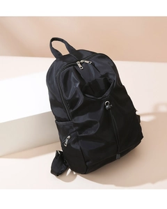 Macro view showing the durable nylon texture and drawstring front pocket of the black backpack