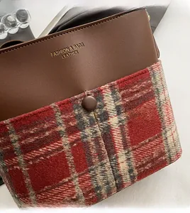 Detail of plaid wool fabric and brown leather panel with fine stitching on a shoulder bag