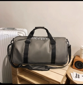 Macro view of grey oxford fabric travel bag featuring black handles and logo detail
